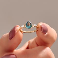 a woman's hand holding an engagement ring with a blue topazte and white diamonds