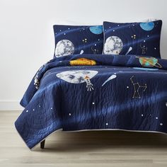 a bed with blue bedspread and space themed comforter set on top of it