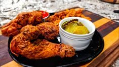 fried chicken and dipping sauce on a black plate