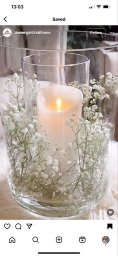 a glass vase filled with white flowers and a lit candle