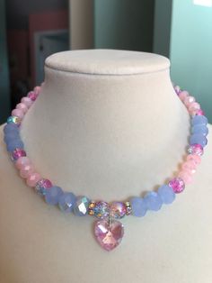 This aurora borealis pink heart charm choker stuns with pink and blue crackle glass beads, light blue aurora borealis faceted glass beads, and light pink faceted glass beads. This piece is exquisite in its ability to reflect light and color. Pink Crystal Necklace With Heart Charm, Pink Heart Charm Choker Necklace, Pink Crystal Choker Necklace As A Gift, Pink Crystal Choker Necklace For Gift, Pink Heart Beads Choker Jewelry, Pink Crystal Beaded Necklace For Gift, Pink Crystal Necklace With Faceted Beads, Pink Aurora Borealis, Pink Aurora