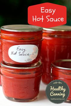 four jars filled with homemade hot sauce sitting on top of a white table next to a red sign that says easy hot sauce