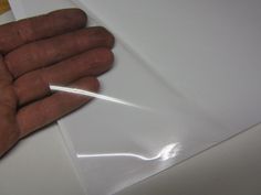 a person's hand holding an object in their left hand on top of a piece of white paper