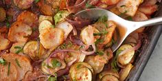 a pan full of cooked vegetables with a spoon in the middle and garnished with herbs