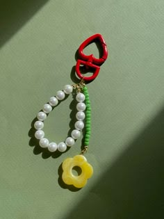 a pair of scissors and beads are hanging on a green surface with a yellow flower