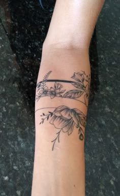 a woman's arm with tattoos on it and flowers in the middle of her arm