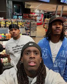 three young men are standing in a grocery store and one is looking up at the camera