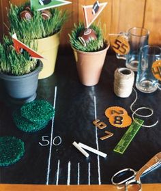 a football themed party table with green grass and decorations on it, including scissors, markers, paper flowers, and other items