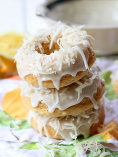 there are three donuts with icing and coconut on the top one is stacked up