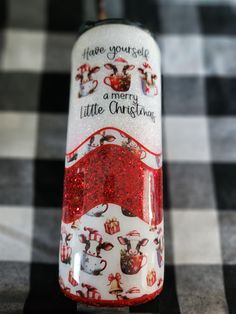 a glass bottle with red glitter on it sitting on a checkerboard tablecloth