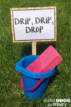 a blue bucket with a pink sponge in it sitting next to a sign that says drip drop