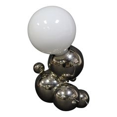 a white ball sitting on top of some shiny silver balls in front of a white background