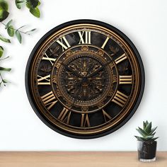 a black and gold clock sitting on top of a table next to a potted plant