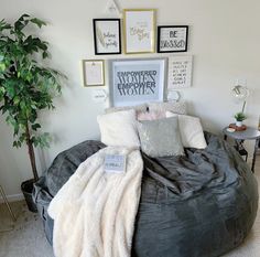 a large bean bag bed in a bedroom with pictures on the wall and plants behind it