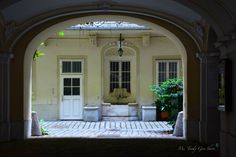 an archway leading into a white building with potted plants