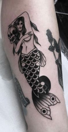 a black and white photo of a mermaid with a skull on her arm