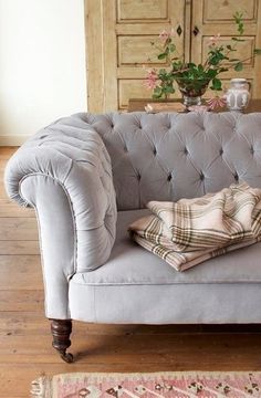 a gray couch sitting on top of a hard wood floor next to a wooden door