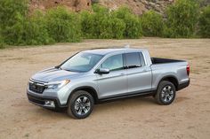 a silver honda pickup truck parked in the dirt