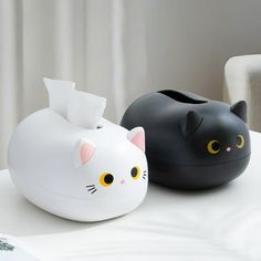 two black and white cat shaped vases sitting on a table next to each other