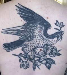 the back of a woman's tattoo with a bird and flowers on her chest