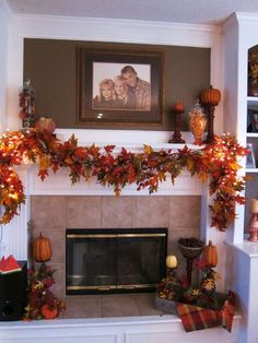 a fireplace decorated with fall leaves and pumpkins