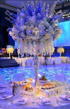 a tall centerpiece with white flowers and blue lights is on display at an event