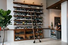 there is a ladder in the middle of this room that has bottles on it and people at the counter