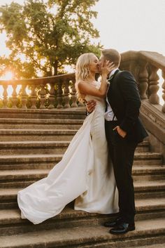 a bride and groom kissing on the steps