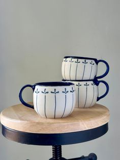 three coffee mugs sitting on top of a wooden table next to eachother