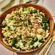 a wooden bowl filled with broccoli, nuts and other vegetables on top of a table