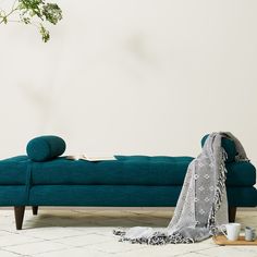 a blue couch sitting on top of a white tiled floor next to a potted plant