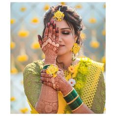 a woman holding her hands up to her face with yellow flowers in the hair and makeup