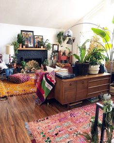 a living room filled with lots of furniture and plants on top of a wooden floor