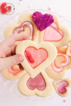 someone is holding up some heart shaped cookies