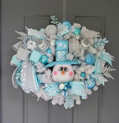 a snowman wreath with blue and silver decorations on it's front door,