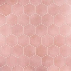 a pink tiled wall with small hexagonal tiles on the top and bottom half