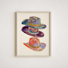 three hats are hanging on the wall in front of a white frame with an orange and blue hat