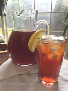 two pitchers of tea sit next to each other on a table with a lemon wedge