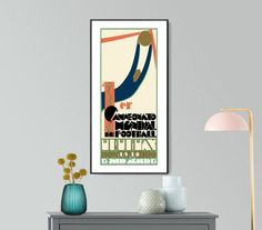 a poster hangs on the wall above a table with a lamp and vase in front of it