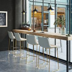 three white chairs sitting at a table with a chalkboard on the wall behind it