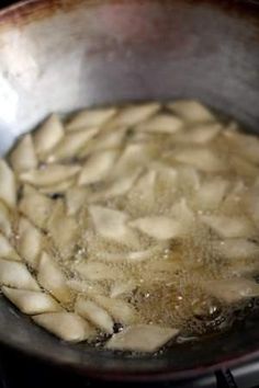 some food is cooking in a frying pan on the stove top with boiling water