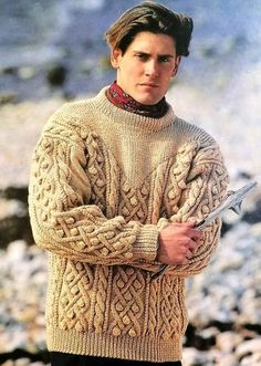 a man in a sweater is standing on the beach