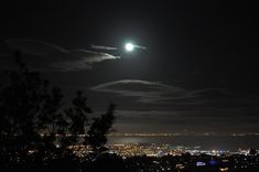 the full moon shines brightly in the dark night sky over a cityscape