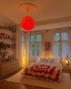 a bed room with a neatly made bed and a red ball hanging from the ceiling