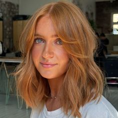 a woman with red hair and blue eyes is looking at the camera while wearing a white t - shirt