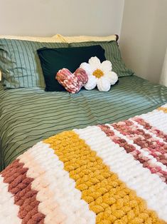 a bed with green and white bedspread next to two pillows on top of it