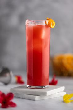 a tall glass filled with red liquid on top of a table