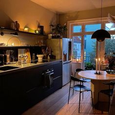 a kitchen with a table and chairs next to an open doored window at night