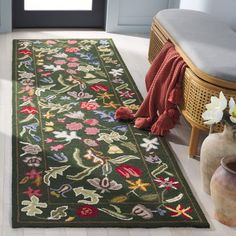 a green rug with flowers on it in a room next to a chair and vase