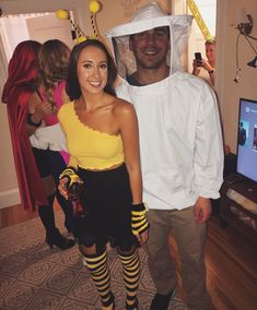 a man and woman dressed up in bee costumes, standing next to each other on the floor